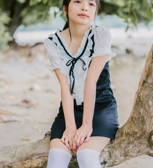 Person sitting cross-legged with eyes closed, looking serene and peaceful.